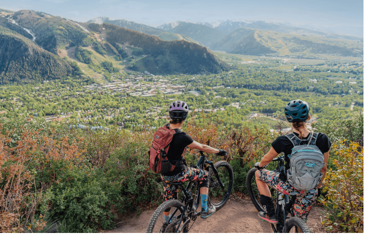 Two women overlook the aspen valley from their vantage point above the town of aspen