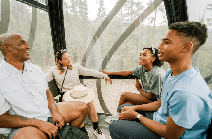 A family sits in the Elk Camp Gondola on a summer day on their way up to the Lost Forest