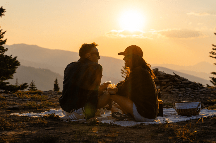 Couple sits atop Aspen Mountain and enjoys a picnic