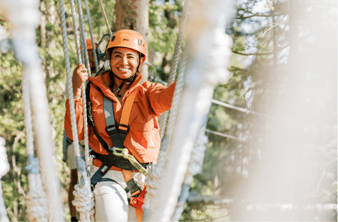 Woman crawls through rope course at Snowmass Lost Forest