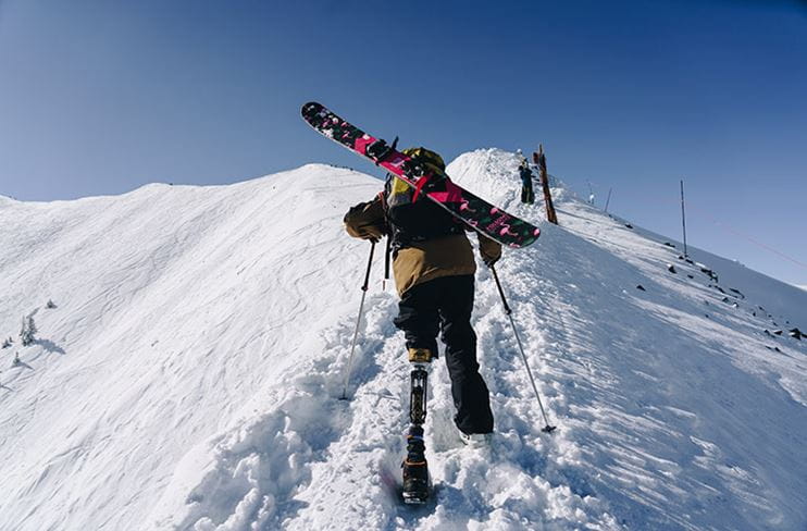 An adaptive skier climbs Highland Bowl