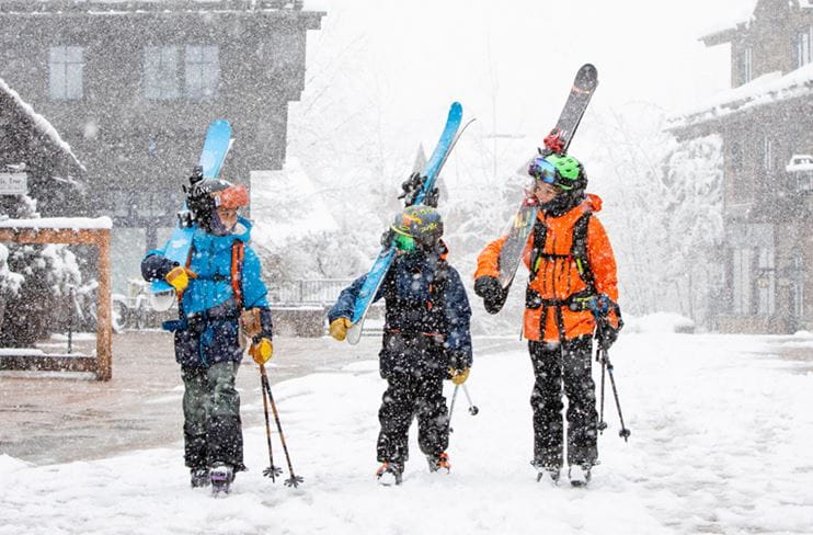 A group of boys walks with their skis at Snowmass Base Village