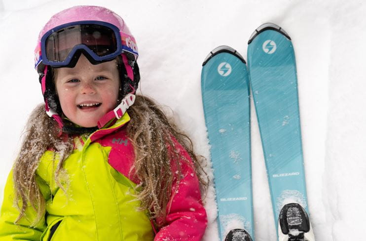 A young skier smiles with her rental skis