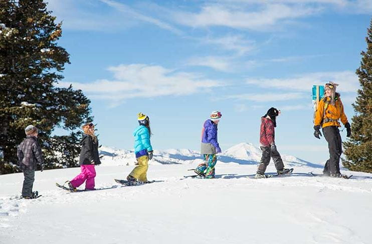 A row of children enjoys a snowshoe tour at Snowmass