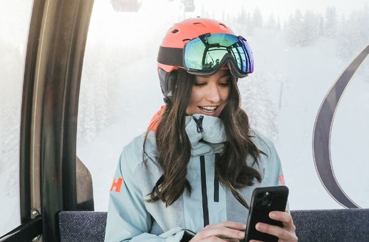A skier taps on the Aspen Snowmass App on a gondola