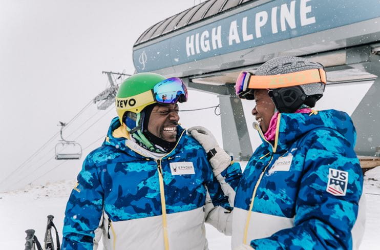 Two skiers laugh at the top of the High Alpine lift.