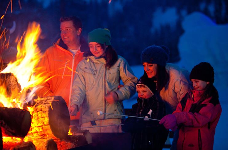 A family warms by the fire at Ullr Nights
