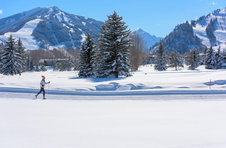 Cross-country skiier on a flat trail with mountains in the background