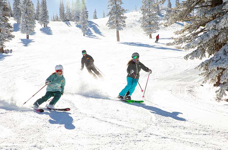 A family of three descends an easy ski run at Snowmass