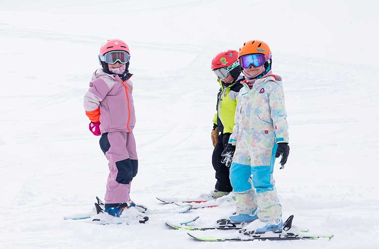 Three kids take a ski lesson at Aspen Snowmass