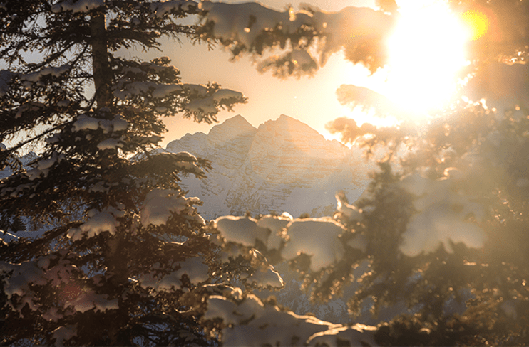 Pyramid Peak is illuminated by the sun as we see it through snow covered pine trees
