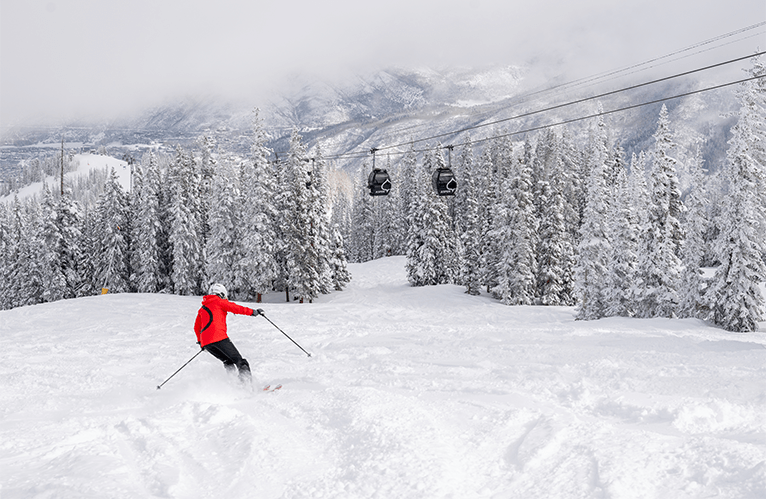 Aspen Snowmass Ski Instructor in deep powder under the Aspen Gondola 