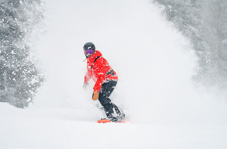 Aspen Snowmass Snowboard instructor rides in deep powder on a snowy day