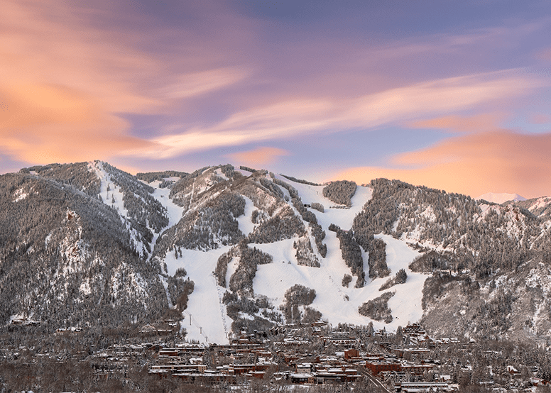 Beautiful view of winter Aspen Mountain, town of aspen at the foot of the hill, with a purple and pink sunset above