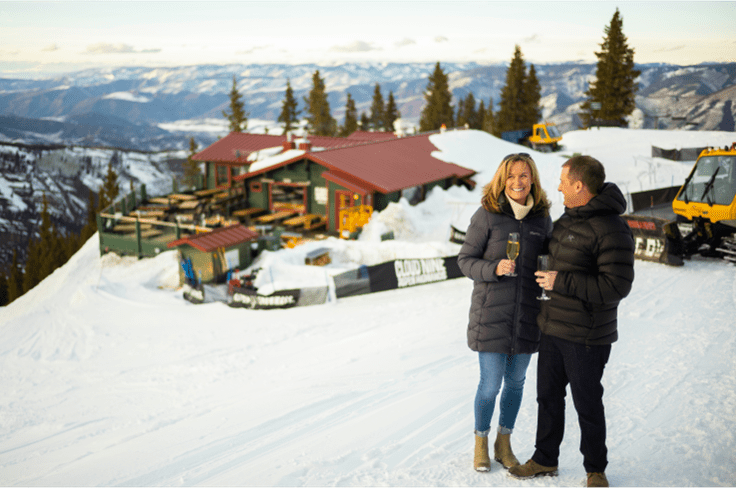 a couple smiles and cheers at their snowcat dinner atop aspen Highlands, at Cloud Nine