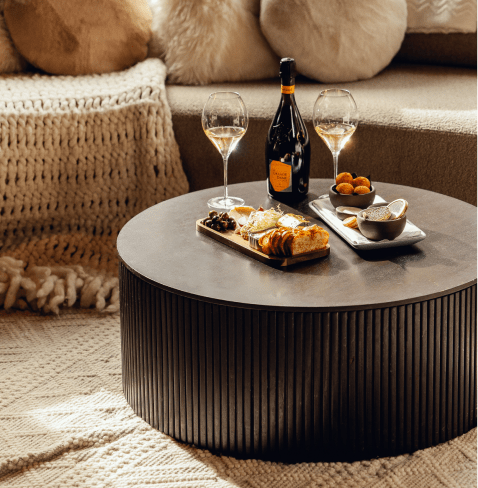 Wood coffee table in front of a white couch, with campaign and appetizers at limelight Aspen Lounge