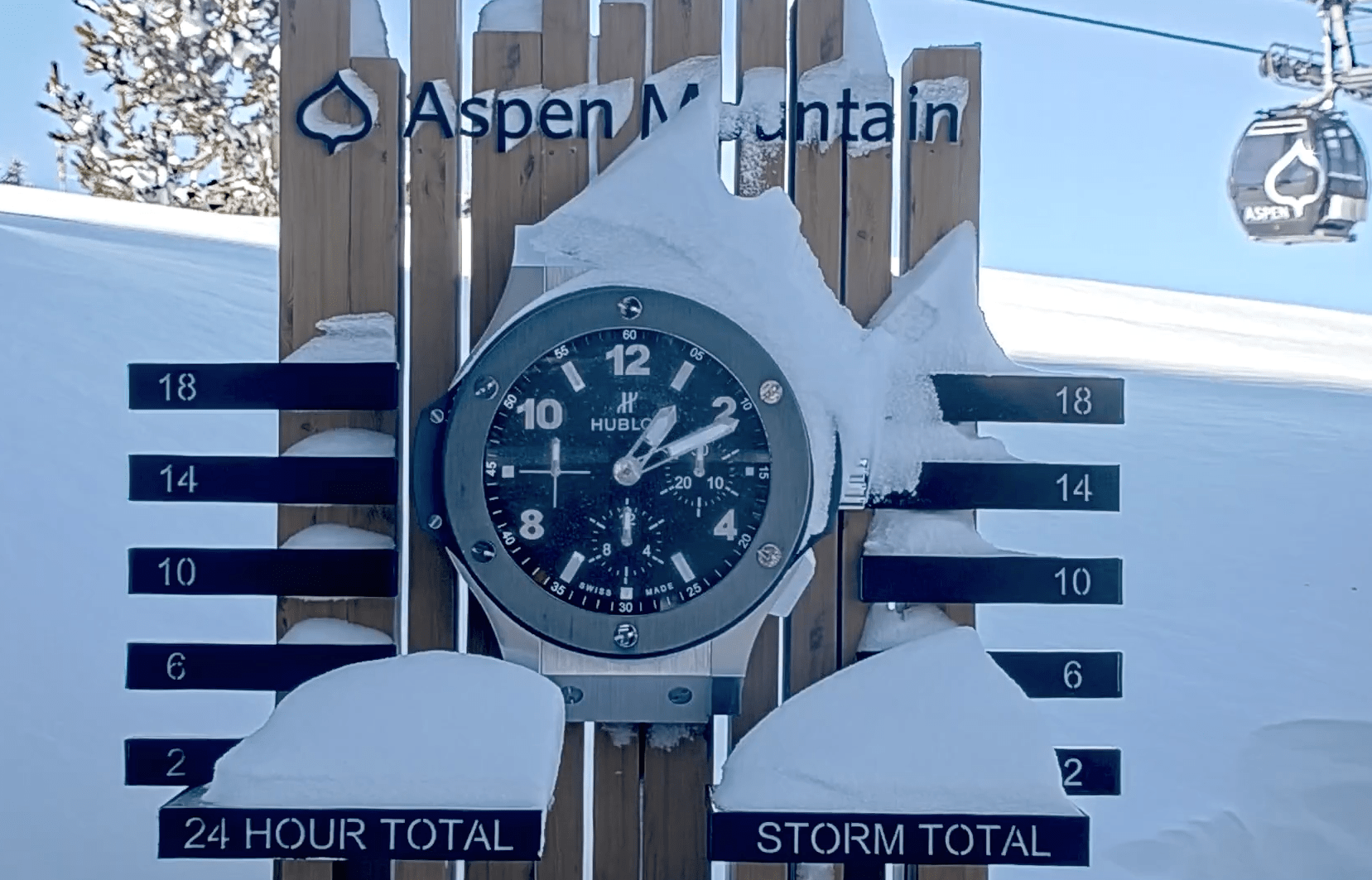 Aspen mountain snow stake, in the shade of the mountain, blue skies behind and snow piled on clock and stake