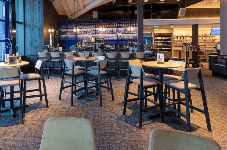 Interior view of buttermilk mountain lodge, moody lighting over tall tables, bar in background
