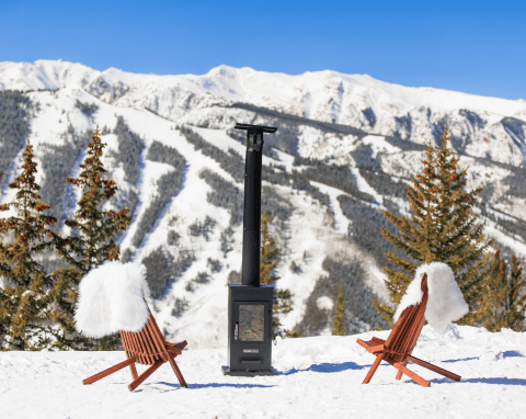 wooden Adirondack chairs with fur throws in the snow, in front of a fireplace, on the slopes of aspen mountain