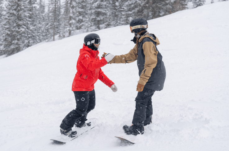 Ski pro helps their student down the hill by lending a hand