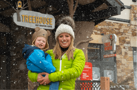 Mother holding son in front of daycare at aspen snowmass while it snows