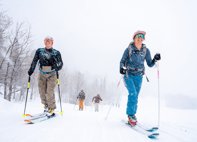 Two woman smile as they uphill on a snowy day to breakfast at Buttermilk Resort