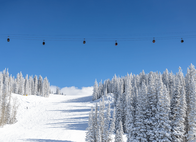 Bluebird skies with the Gondola running high over the ski runs of aspen mountain