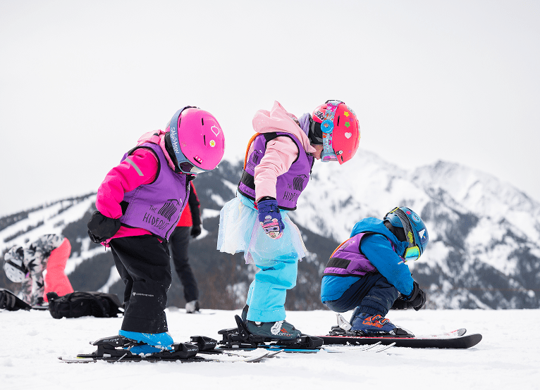 Three kids on buttermilk, all looking down at their gear