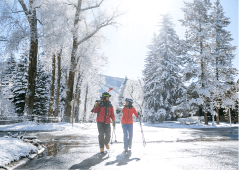 two people walk down a wet street, as snow melts on a sunny winter morning in Aspen snowmass