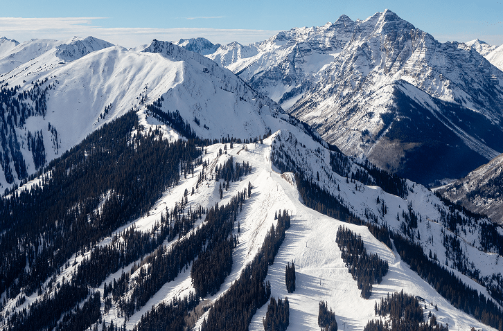 Blue bird ski day at snowmass, elk mountain range rises up behind the ski runs