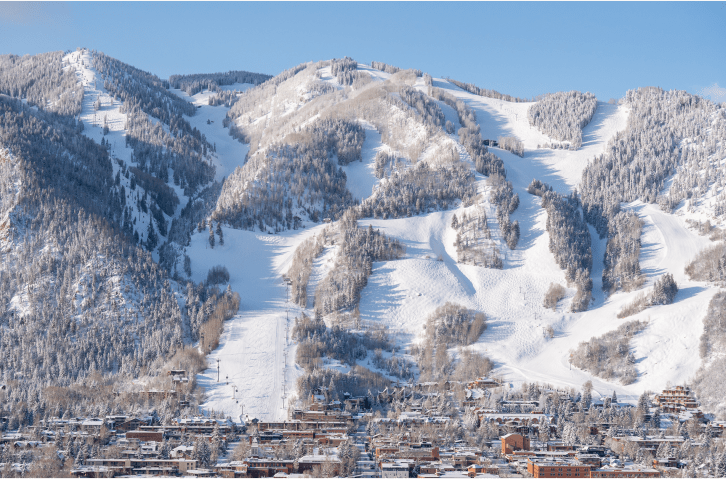 Aspen mountain ski resport from a distance, on a blue bird day. White ski runs and the town of aspen blanketed below