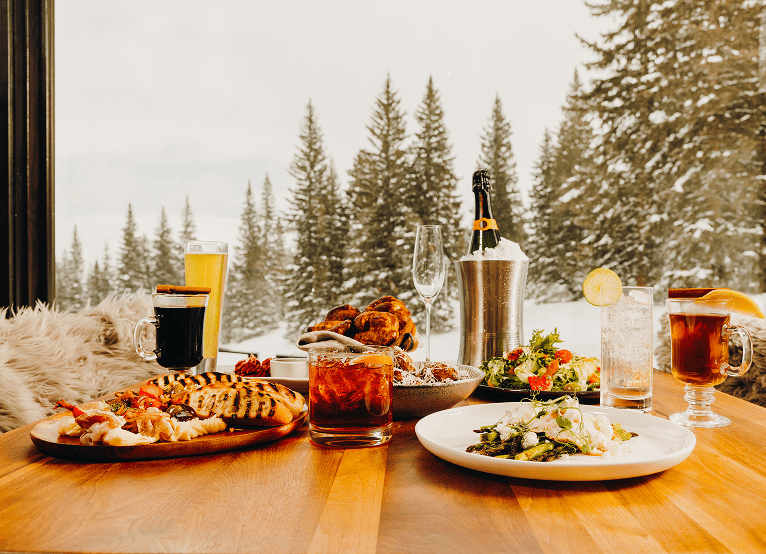 Array of food on table in Aplin room on snowmass, gray skies out the window and warm, delicious food on the table