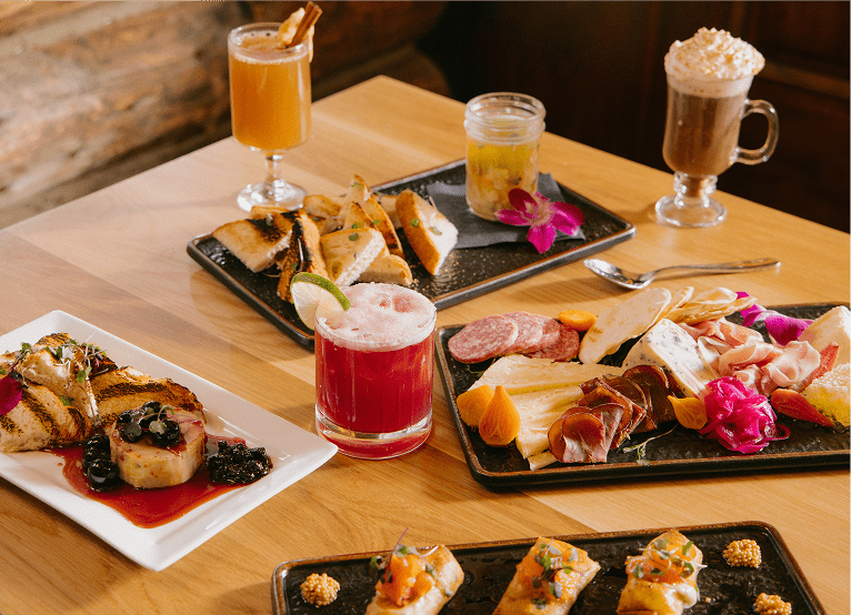 Plates of food and mixed drinks on a table at the Cabin at snowmass