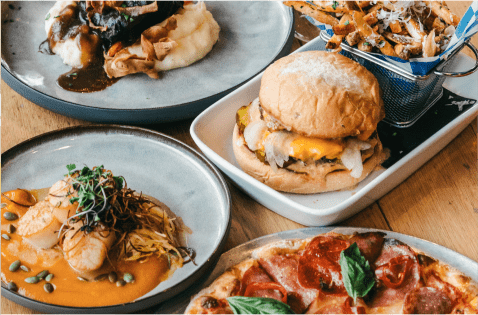 various plates of food at Limelight Aspen, burger on toasted bred, pizza, chicken curry, and more