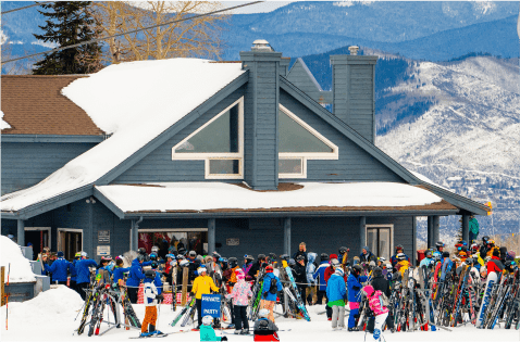 Exterior view of Spider Sabich, where people gather to try Hot Dog Hanz on a sunny day at Snowmass ski resort