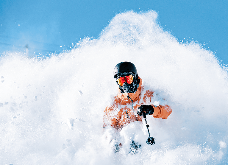 Man skies in deep powder under blue skies at aspen snowmass