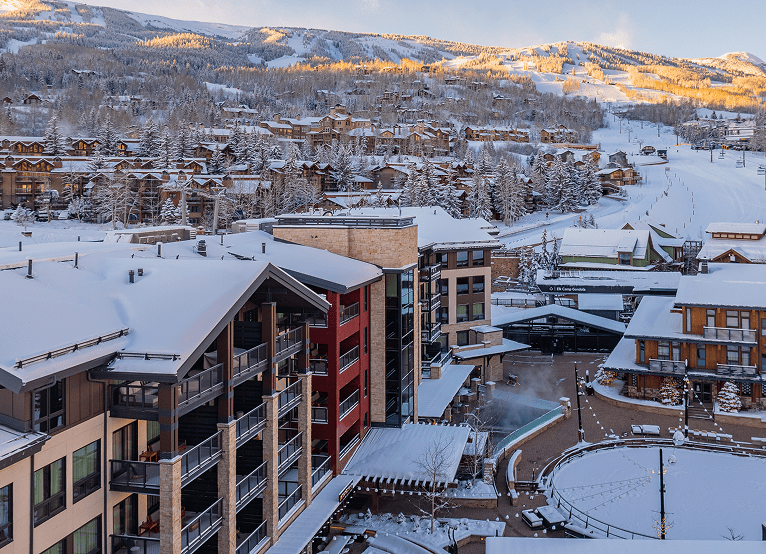 Limelight snowmass at dawn, tall hotel over an ice rink and ramed by the sun rising of snowmass ski resort