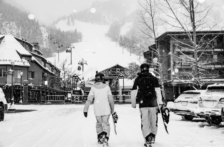 black and white image of couple walking own main street on a snowy day, towards the gondola