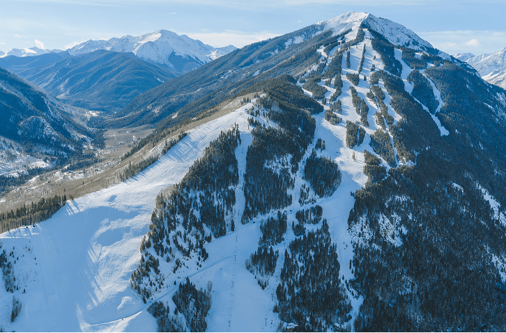 Aerial view of Aspen Highlands, snow packed hills, under blue skies