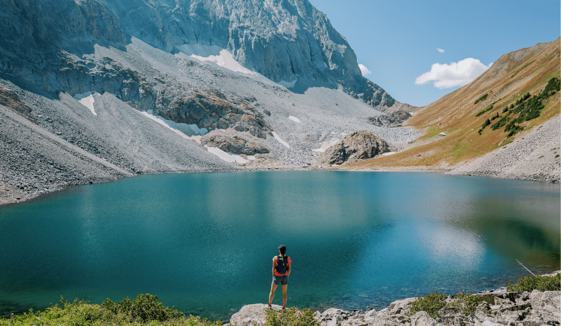 Blue alpine lake under a blue summer sky, rocky mountains surround the lake