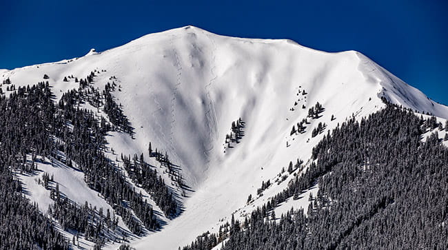 Highland Bowl in the middle of winter with ski tracks crossing its surface