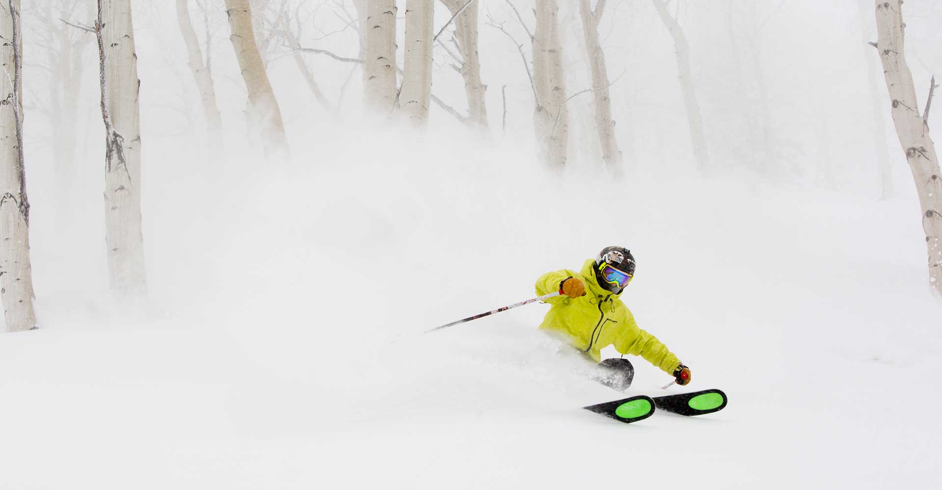 A skier emerges from the trees and powder at Aspen Snowmass