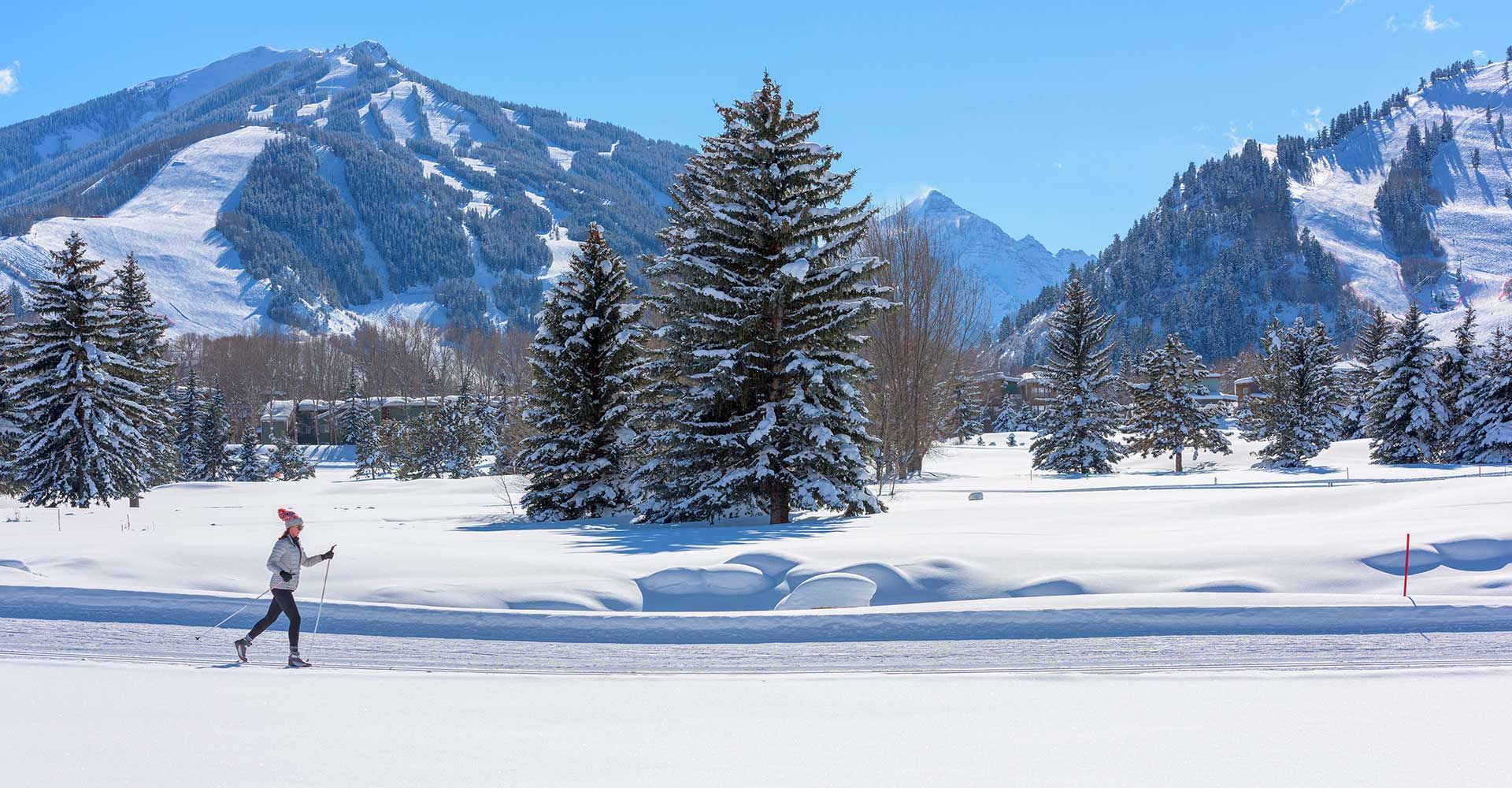 A woman enjoys Nordic skiing at Aspen with Pyramid Peak in the distance.