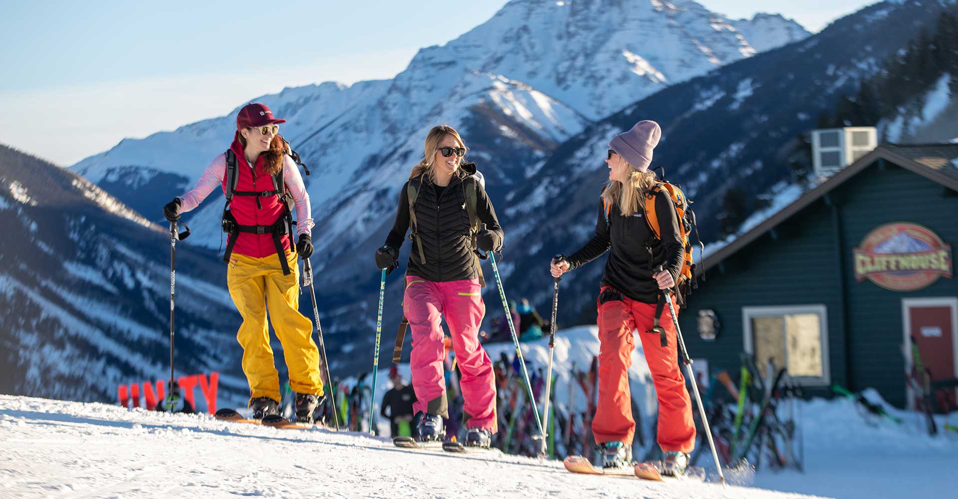 Three friends reach the top of Buttermilk on uphill skis