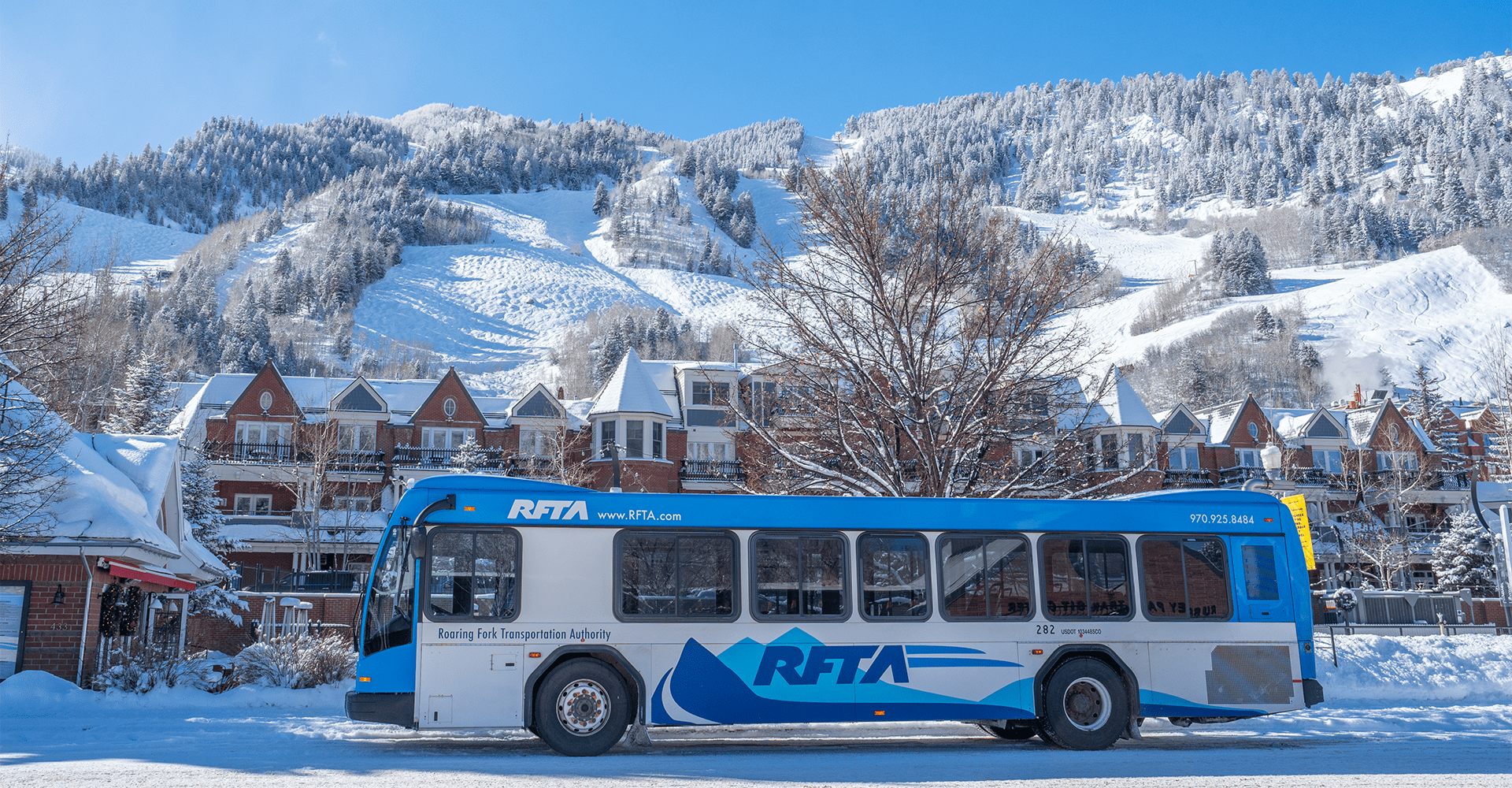 RFTA bus drives through downtown Aspen, with Aspen Mountain illuminated in background