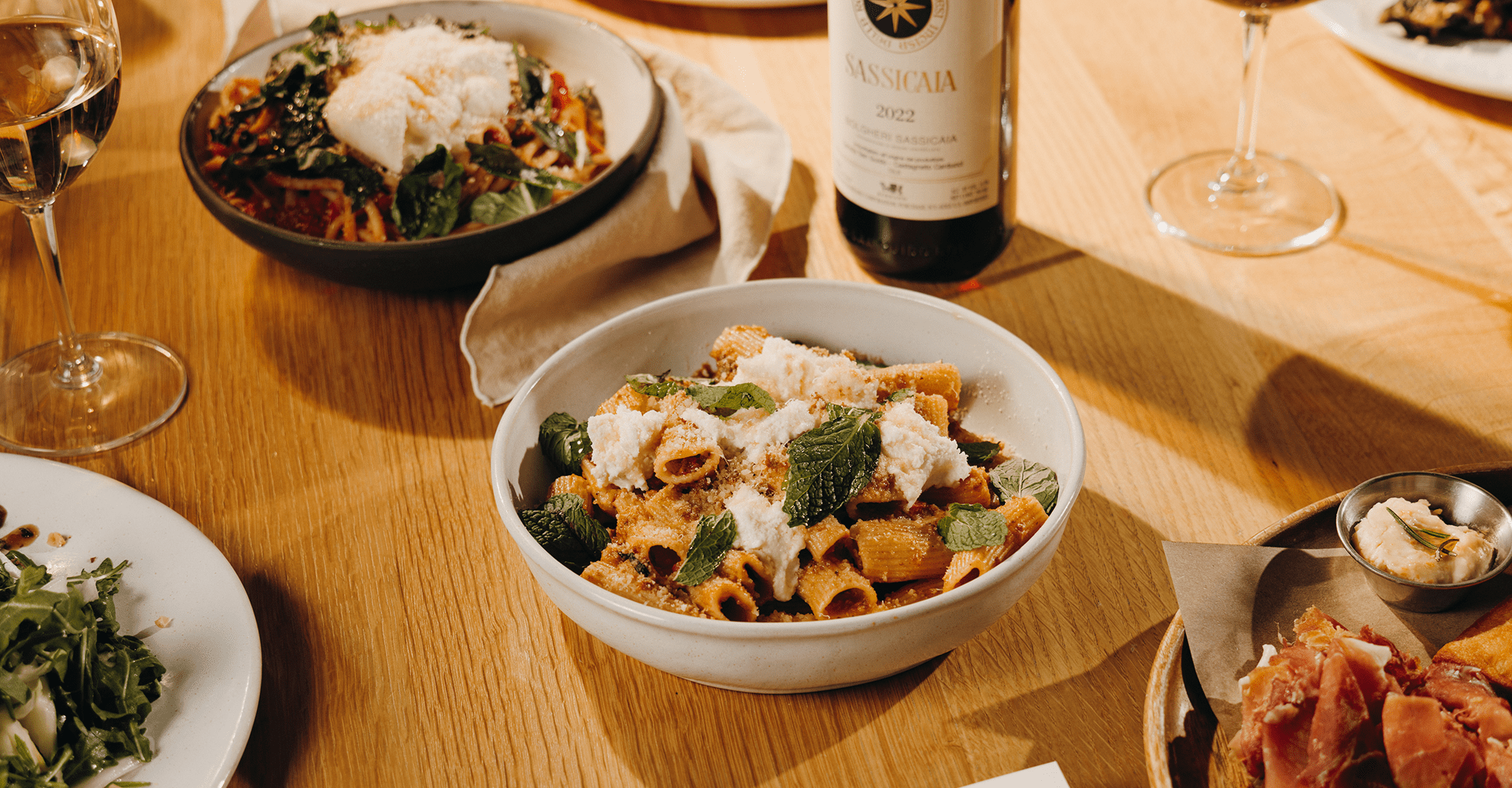 an array of pasta dishes displayed next to a bottle of fine wine at Sam's, atop Snowmass Mountain