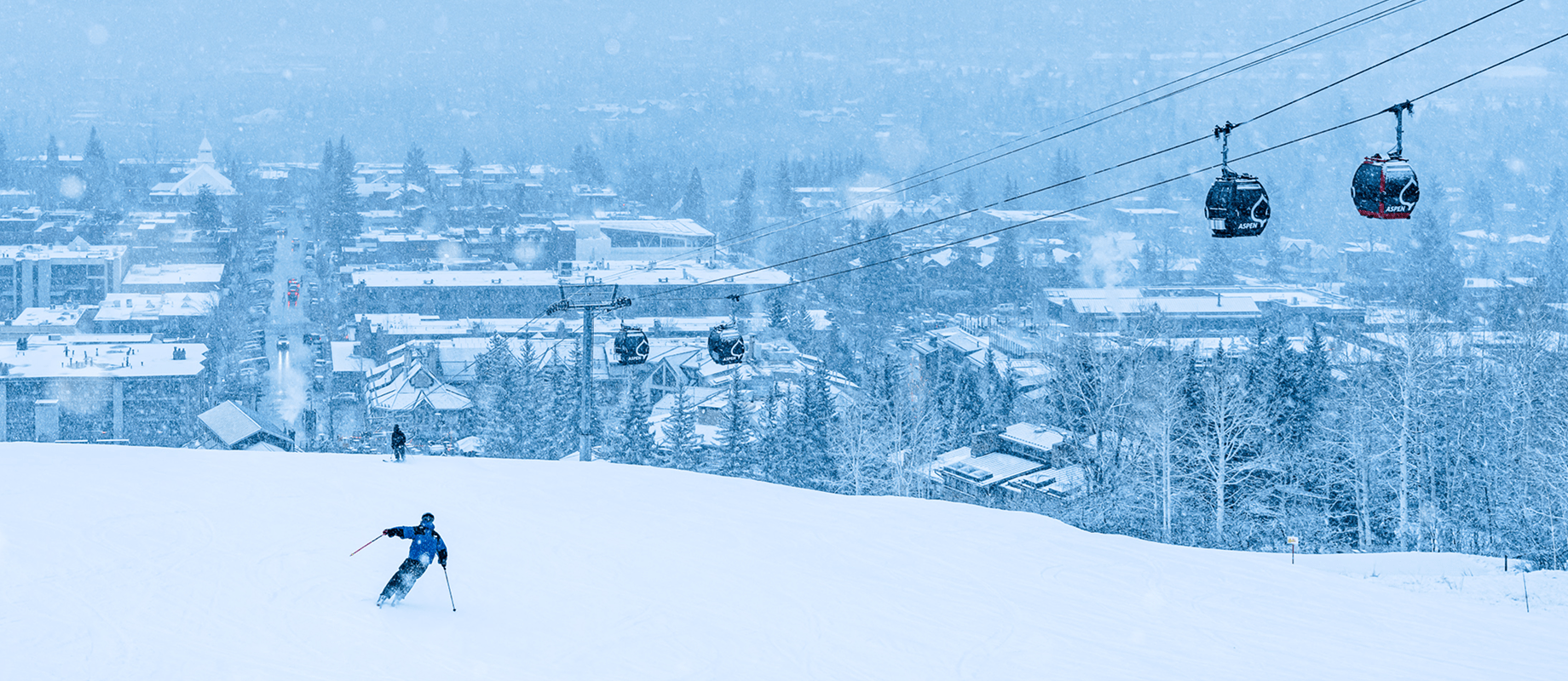 skier in snow on a cloudy, dark day at aspen as snow falls