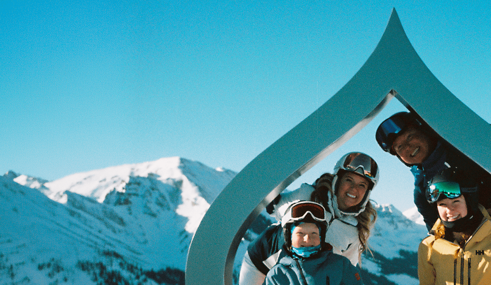 family poses around the aspen leaf on snowmass