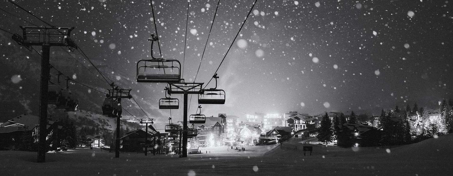 Black and while image of snow falling above Snowmass Base Village.